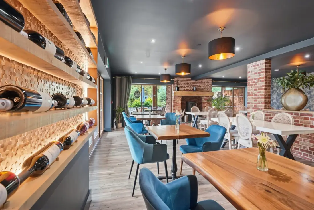 The restaurant at Edge//Noko with wine racks, blue chairs and a view over the water