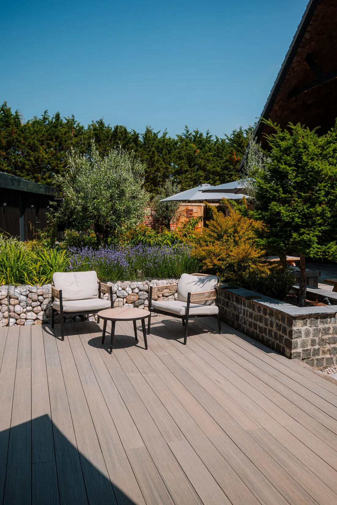 A timber terrace with garden chairs beside the lake