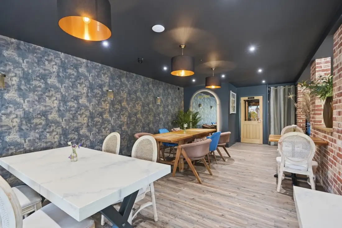 A dining room with teal walls and wooden chairs